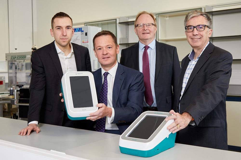 Four workers from Abingdon Health holding up 2 of their devices