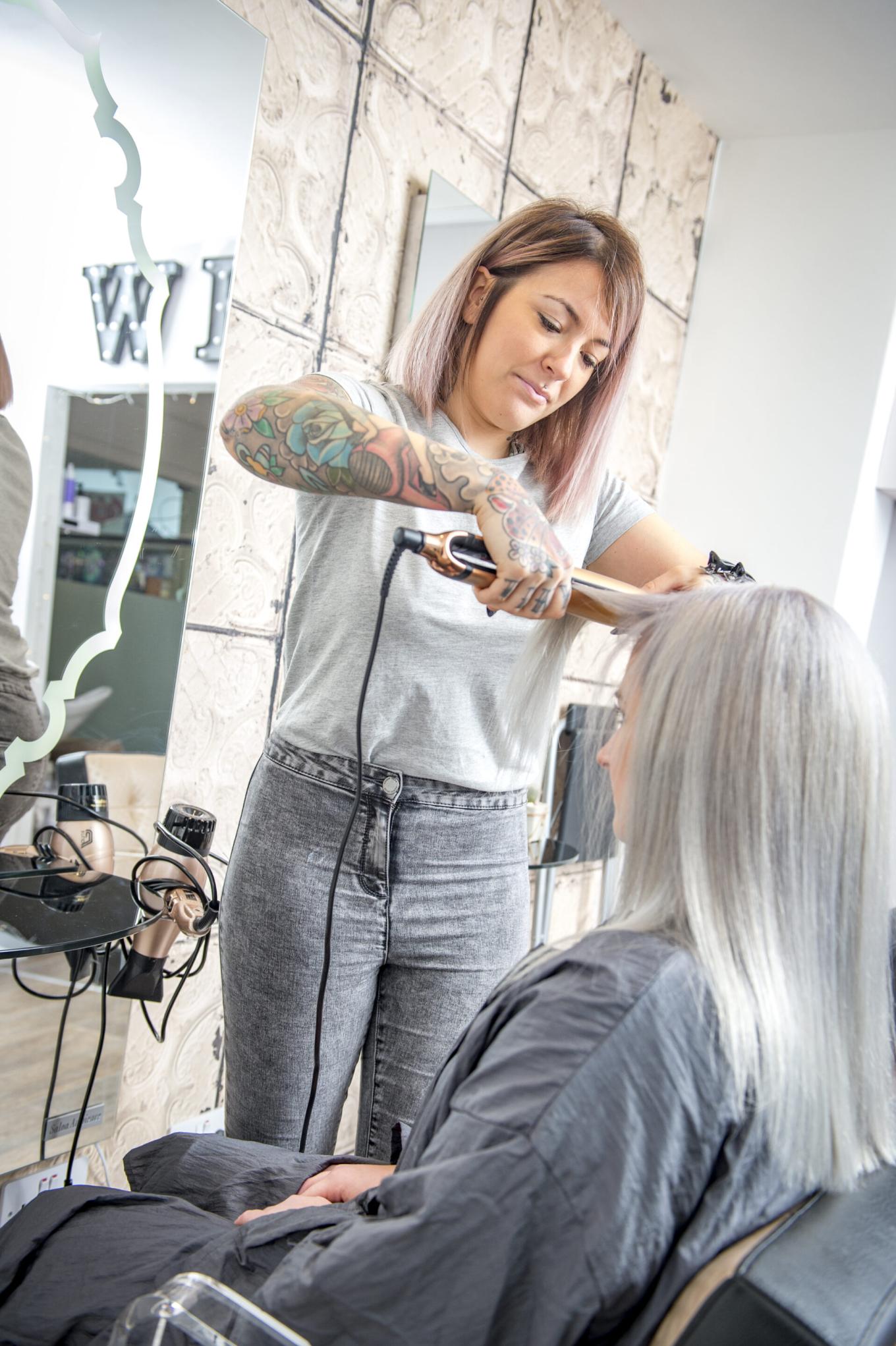A hairdresser straightening a woman's hair in a salon