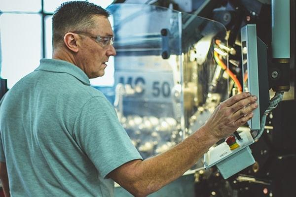 A Hanson Springs employee operating a manufacturing machine on their premises