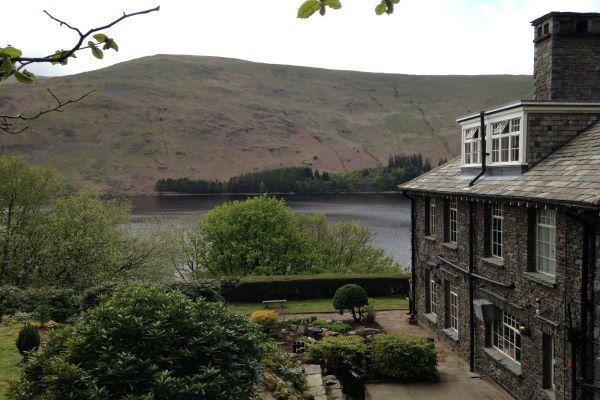 Exterior of Haweswater Hotel surrounded by trees, a lake and hill