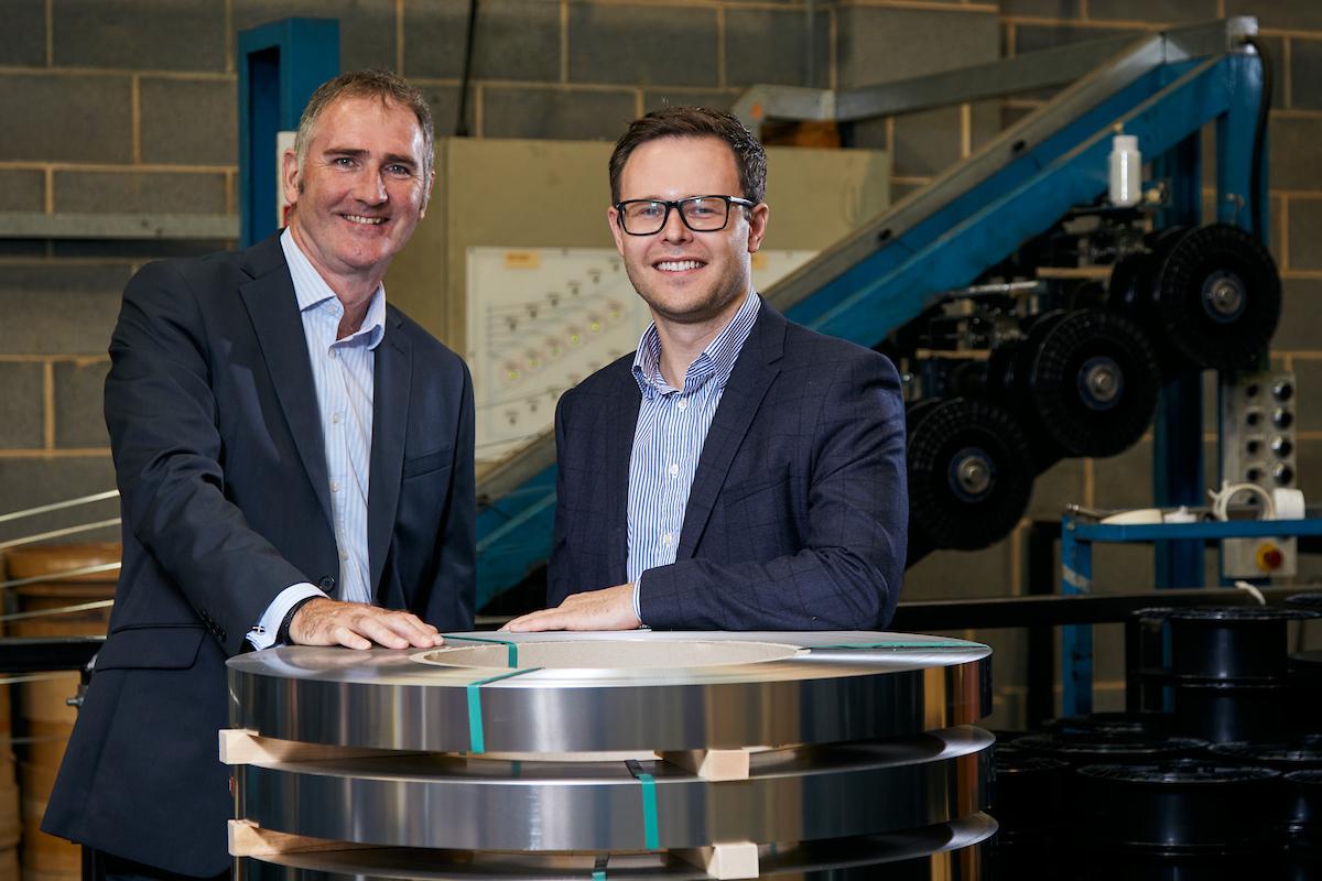 2 men in suits stood in a metal supplier factory