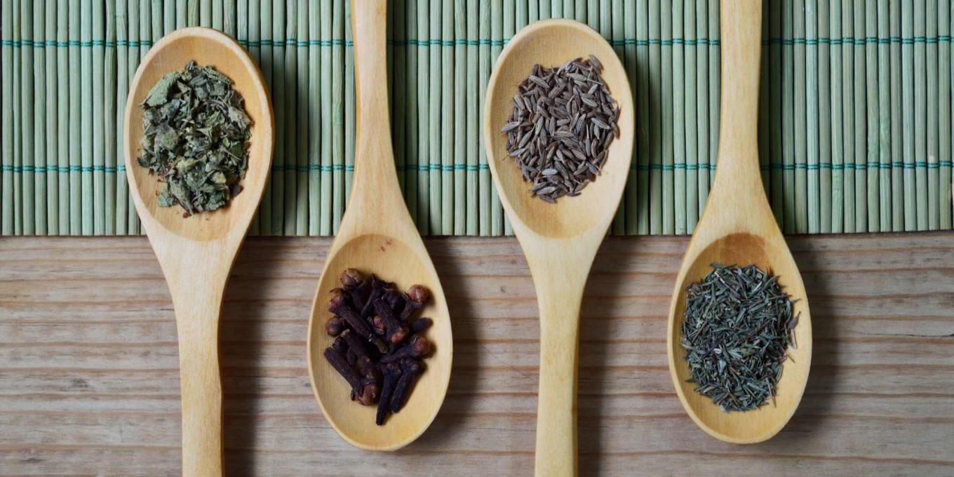 4 wooden spoons filled with a variety of seeds rested on a table