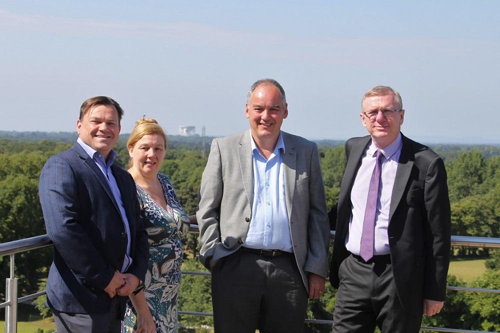 Three men and a women stood on a balcony overlooking a forest area