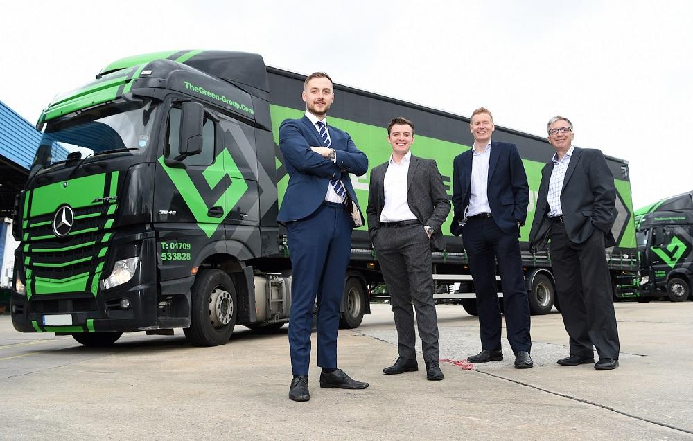 4 men in suits stood in front of a Mercedes Benz lorry