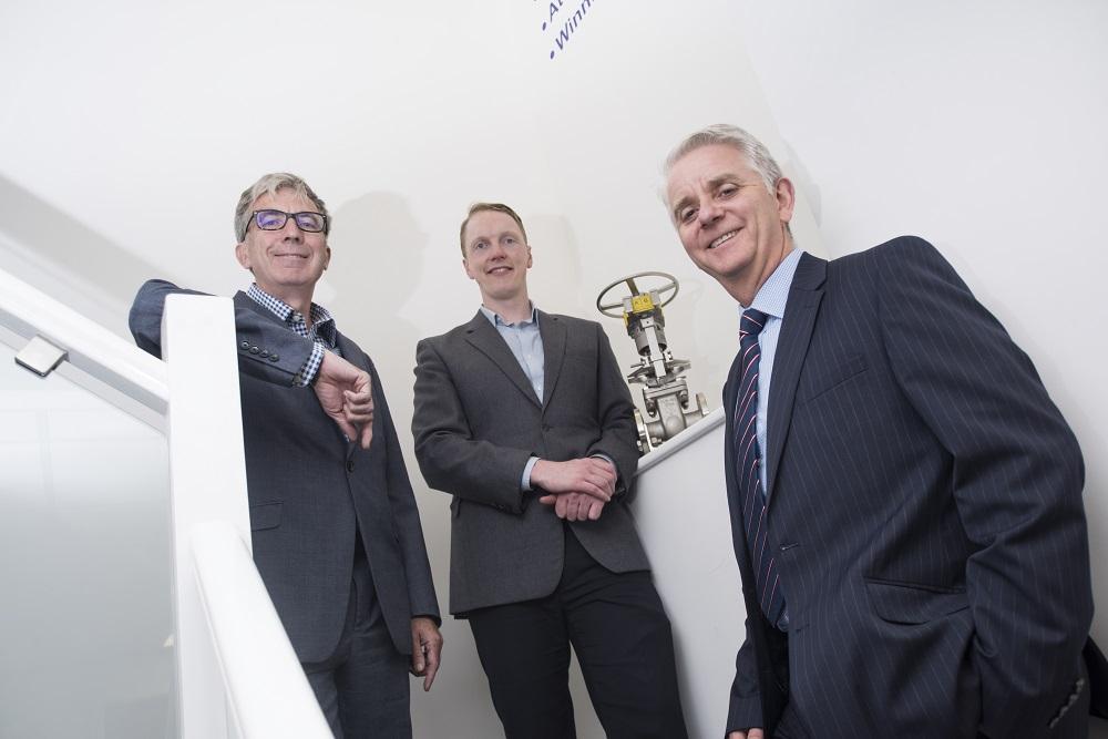 3 men stood on a the stairs in an office building