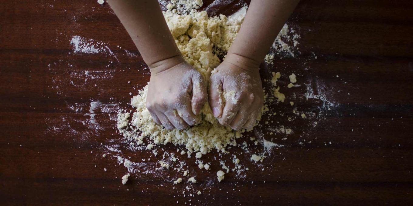 A close up of hands kneading dough on a worktop
