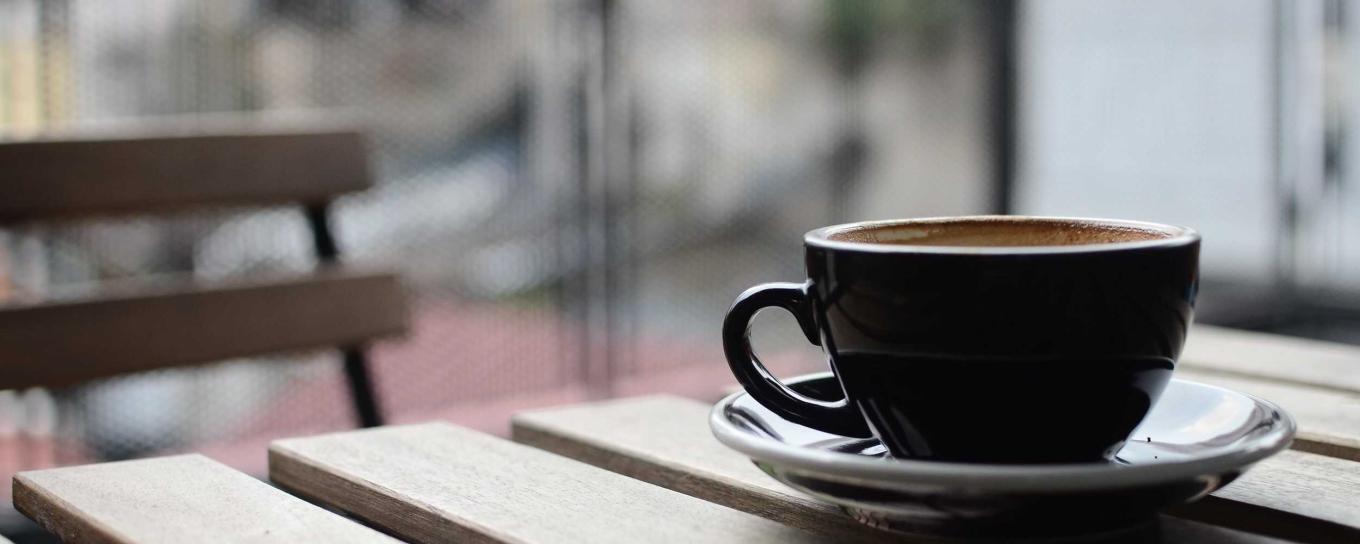 A cup of coffee resting on a wooden table