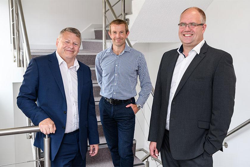 3 men stood on the stairs in an office building