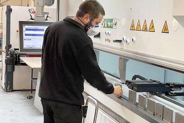 A man wearing a face mask working on a precision metal manufacturing line