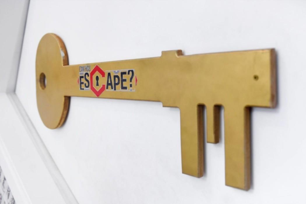 A large key on the wall with the word Can You Escape written on it