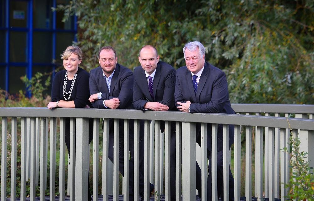 3 men and a woman stood on a bridge outside of an office