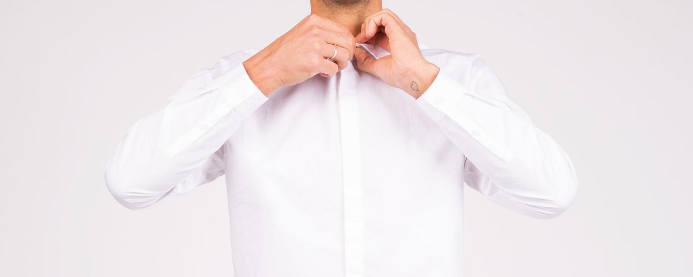 A man fastening the top button of his shirt