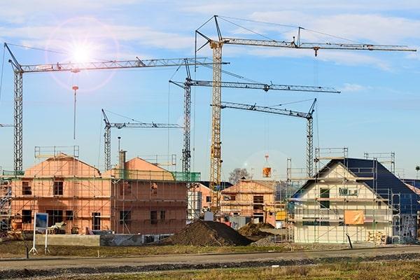 Construction site of many new-build residential homes with cranes above them