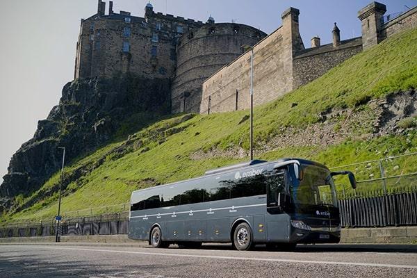 Ember's electric bus travelling down the road, with Edinburgh Castle in the background