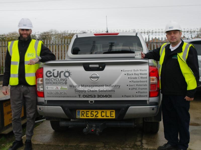 2 men in Hi Vis jackets and hard hats from Euro Recycling Broker stood next to a branded car