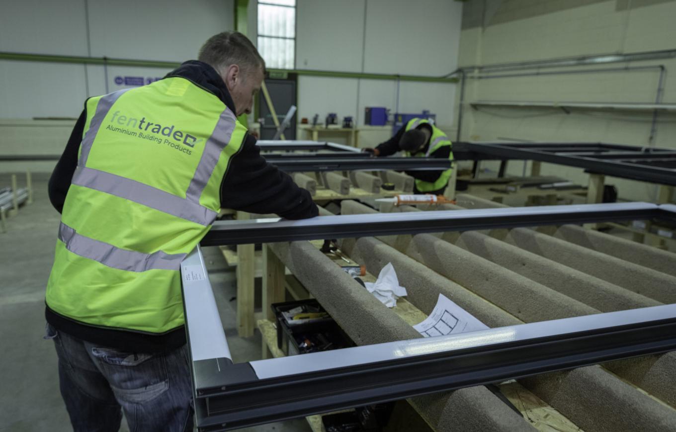 A man in a Hi Vis jacket working in a aluminium windows, bi-fold doors and commercial entrance systems manufacturers