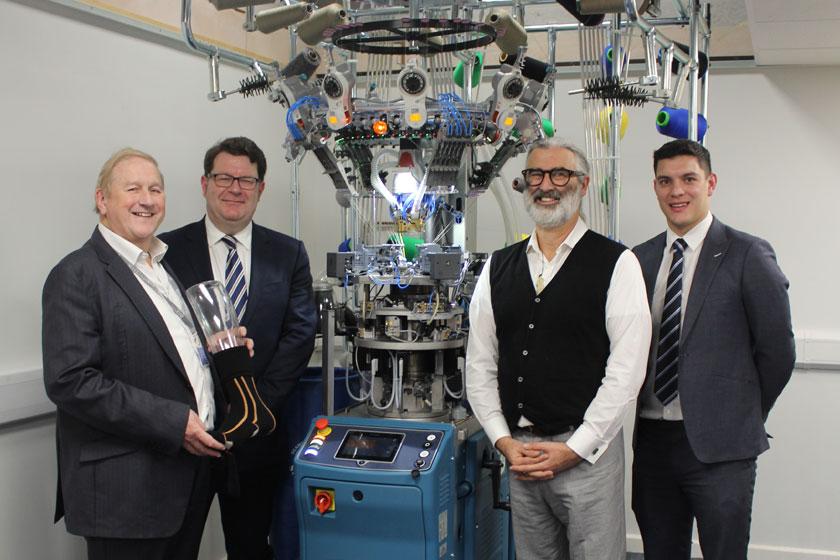 4 men stood next to a textile manufacturing machine