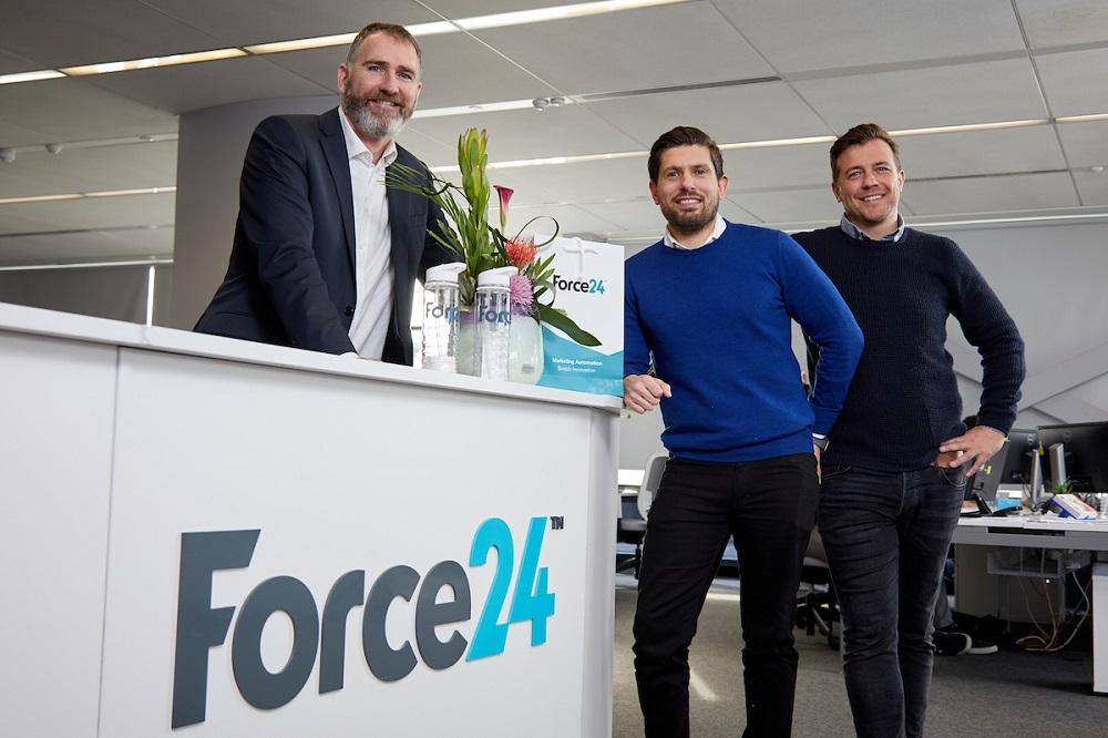 3 men stood near a Force 24 branded reception desk in an office