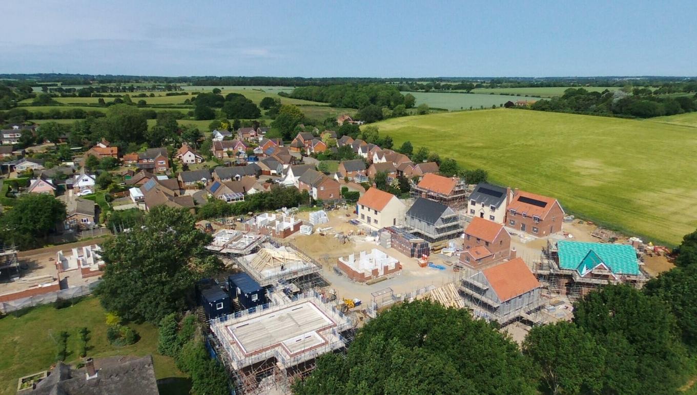 An aerial view of a house construction site with fields in the background