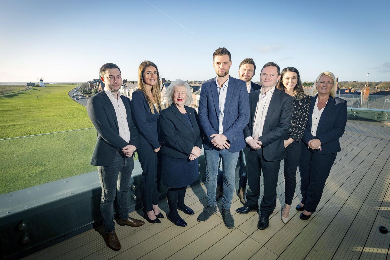 Employees from Get Work stood on a balcony with a field and houses in the background