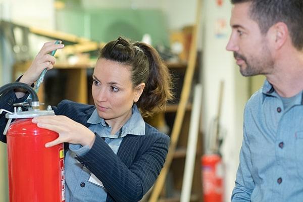 A man and a woman participating in fire safety training on how to use a fire extinguisher