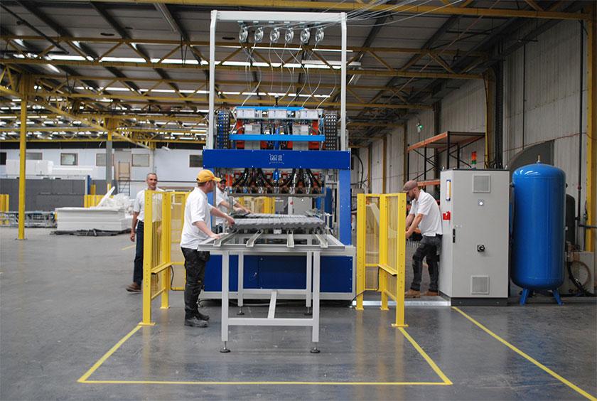 Two male employees working on a machine inside the Green Life Buildings factory