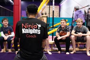 A group of children listening to a coach who has his back to the photo