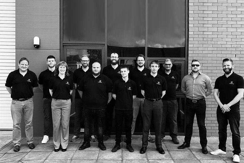 A group of employees smiling and stood outside of an office building