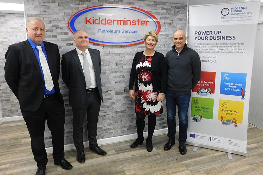 3 men and a woman stood in an office with Kidderminster logo on a brick wall and a MEIF pop in banner next to them