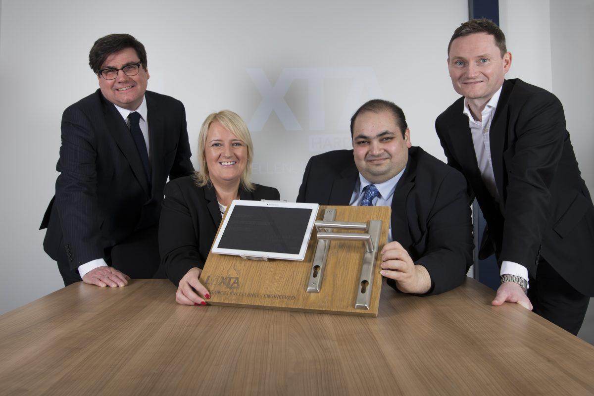 3 men and a women gathered around a table showing their door hardware equipment