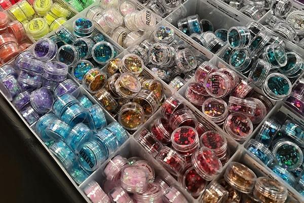 A stall with containers full of pots of different-coloured glitter