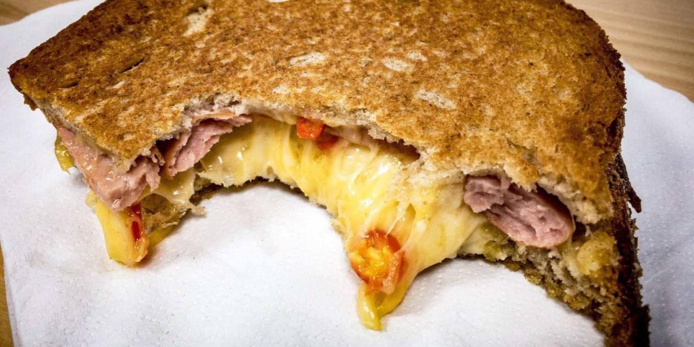 A close up of a meat and cheese toasted sandwich from Meltdown Cheese Cafe