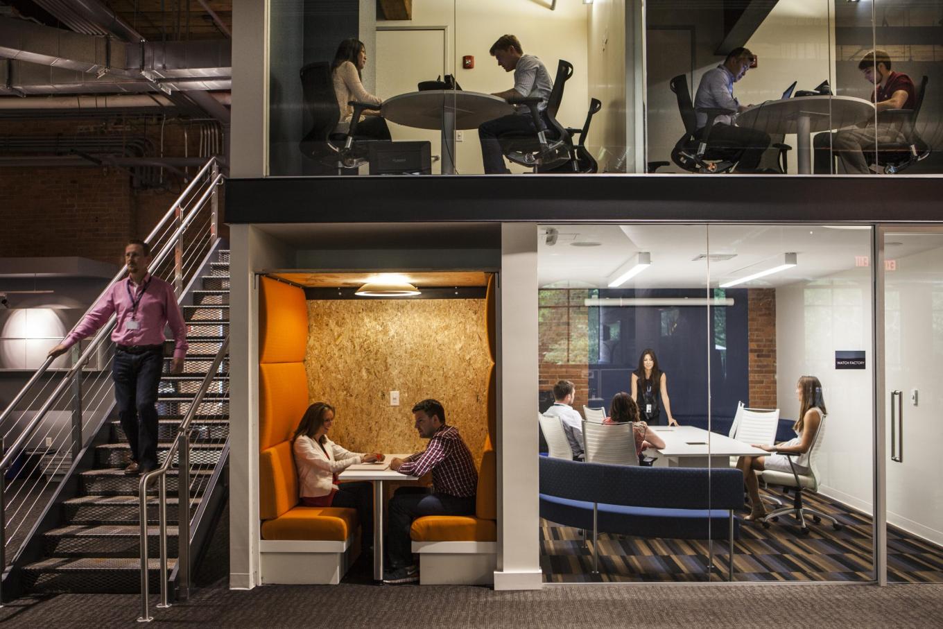 A split level office with various meeting rooms and people working