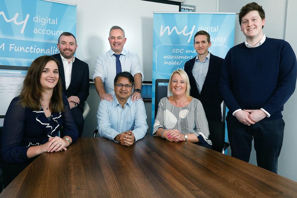 A group of employees from My Digital Accounts smiling and gathered around a table