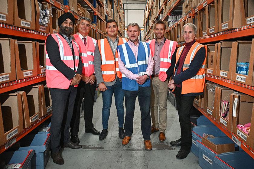 A group of employees from the Online Poundshop wearing Hi Vis vests in a warehouse