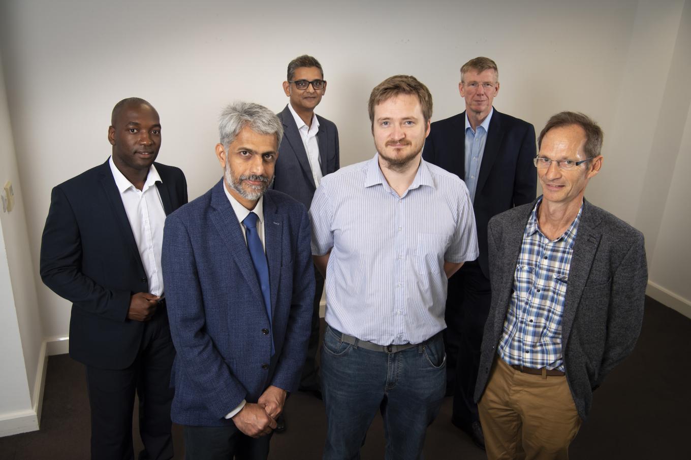 A group of men from Optimus Vitrum smiling and stood in an empty room