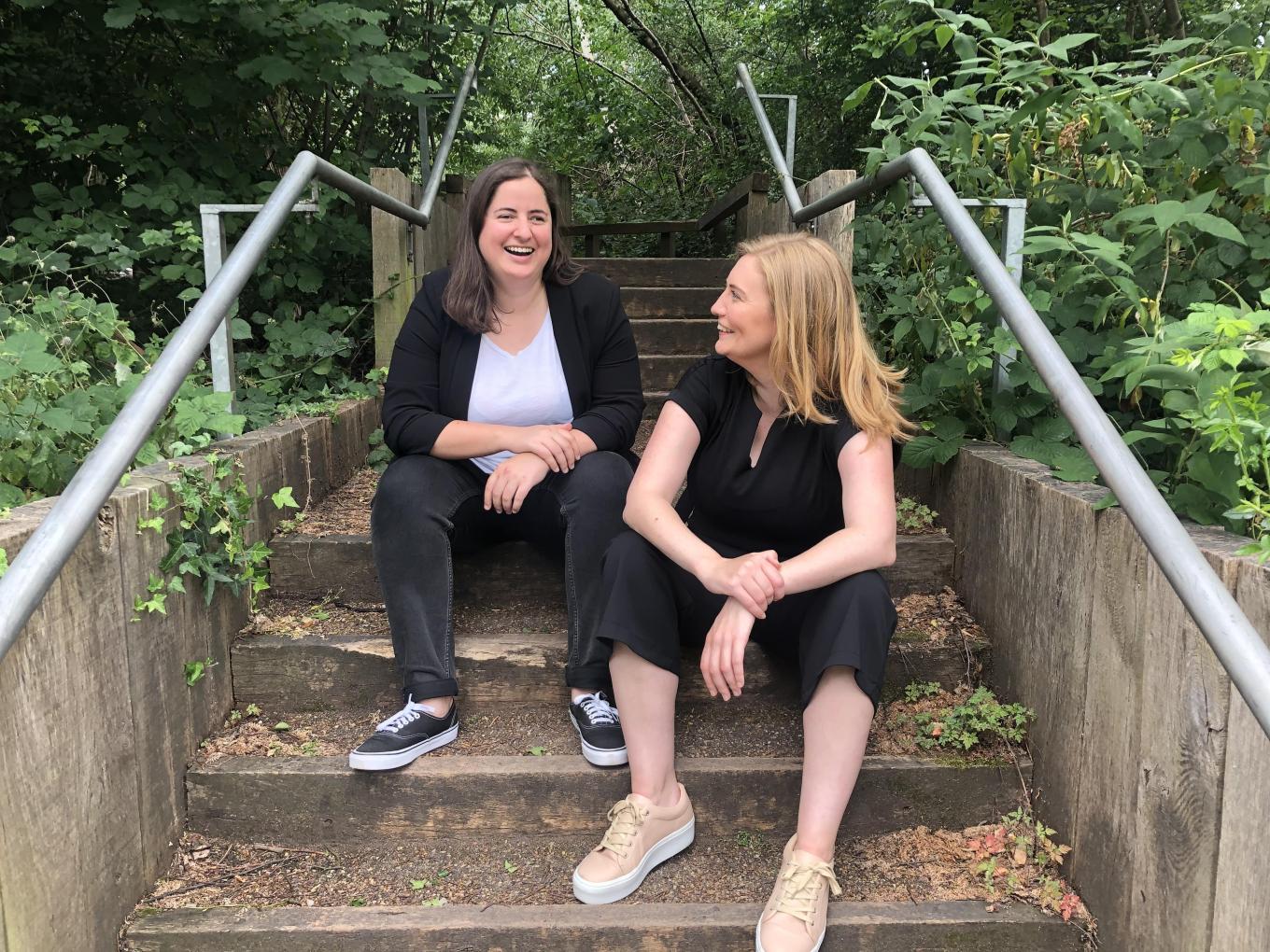 Organise founders founders Bex Hay and Nat Whalley sitting on some outdoor steps