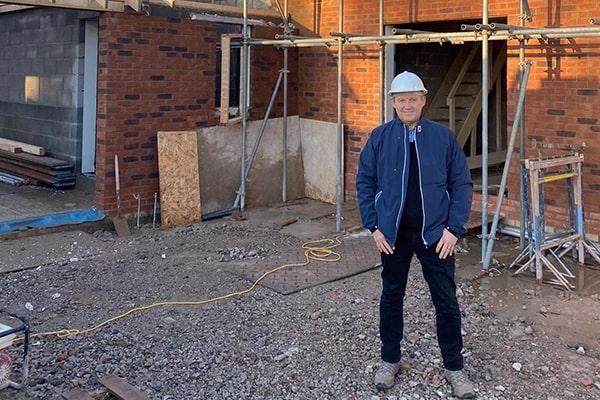 Ian Smethurst of Pearson Quality Homes wearing a hardhat and standing in front of a house under construction