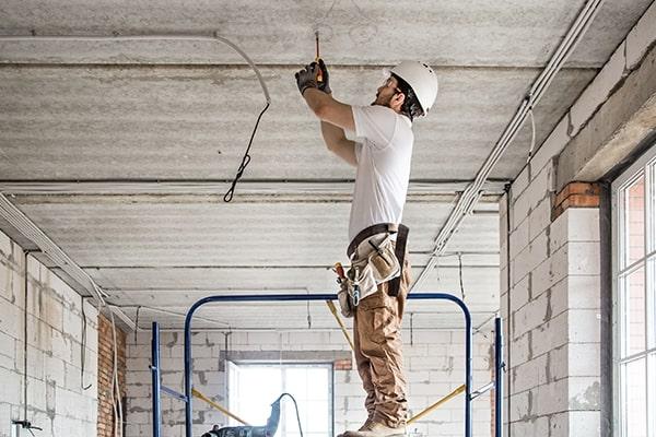 Electrical contractor drilling a concrete ceiling