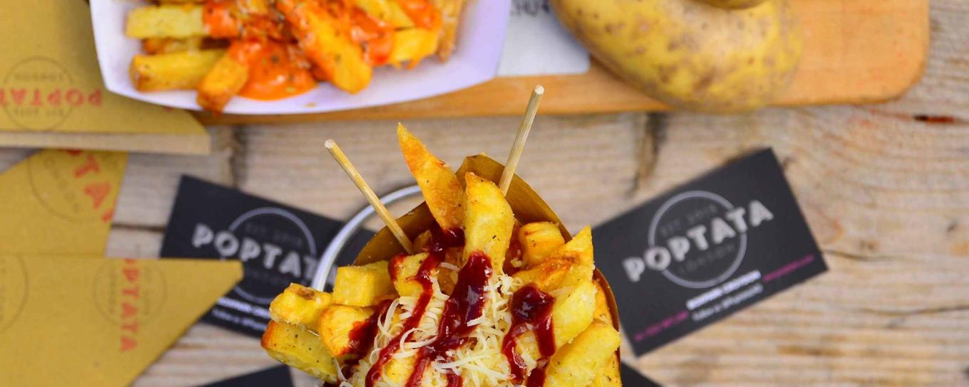 Loaded fries on a table with Poptata business cards next to them