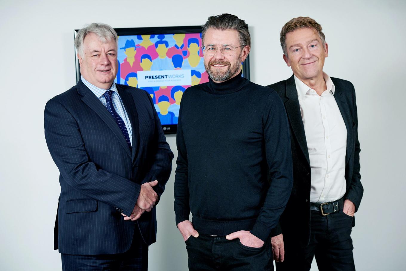 3 men from Present Works smiling and stood infront of a TV screen