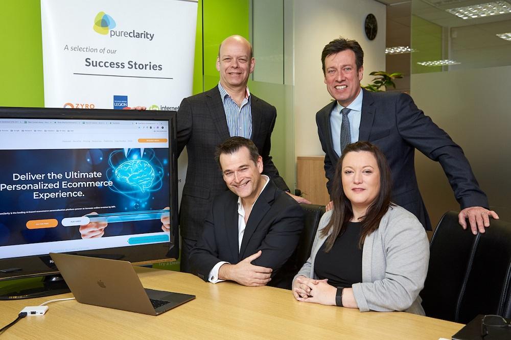  men and a woman around a table with the Pure Clarity web page on a computer screen