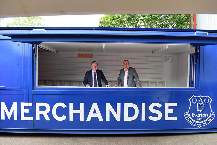 2 men in suits stood in a Everton Football Club branded pop-up shop