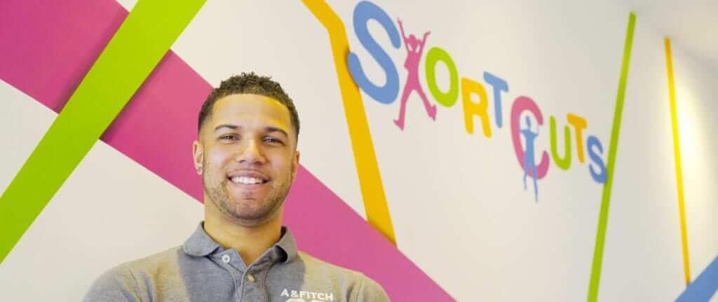 A man from Shortcuts Children's Salon stood in front of a colorful, branded wall