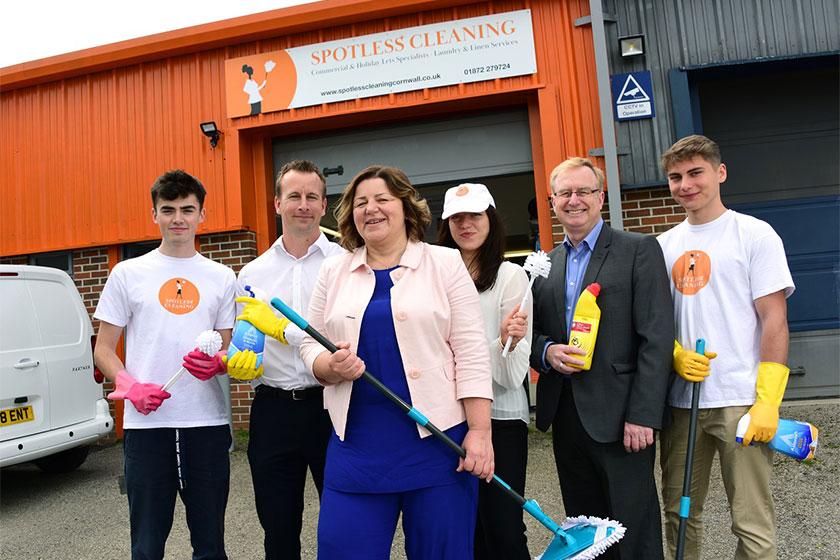 Employees from Spotless Cleaning holding a variety of cleaning products