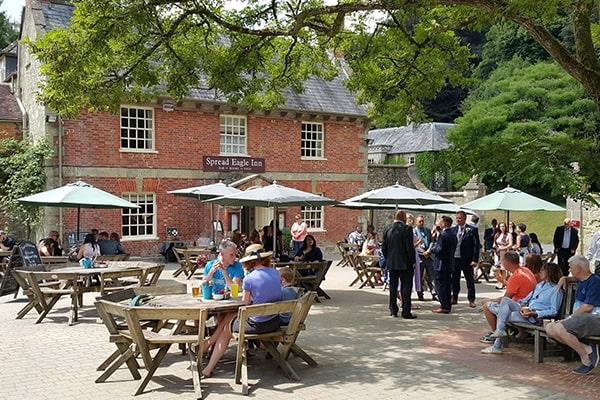 Exterior of the Spread Eagle Inn, with groups of people sat at outdoor tables drinking and eating