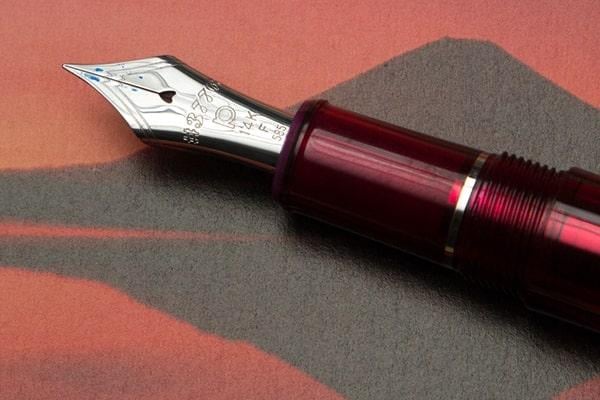 A red Stone Marketing fountain pen with a silver tip