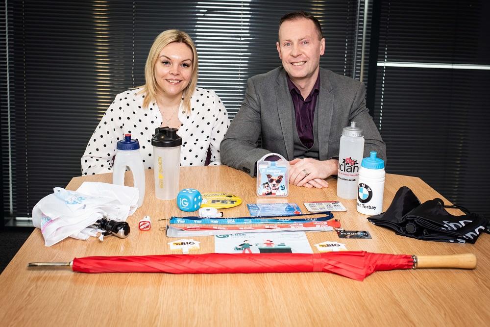 A man and a women sat at a table showing their Branded Items Group products