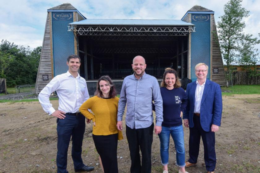 Employees from The Wyldes standing in a field in front of a stage