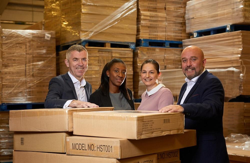 Four employees from Total Racking Solutions standing in between brown boxes